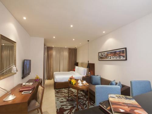 a hotel room with a bed and a living room at Oakwood Residence Whitefield Bangalore in Bengaluru