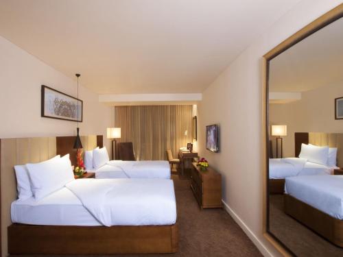 a hotel room with two beds and a mirror at Oakwood Residence Whitefield Bangalore in Bangalore