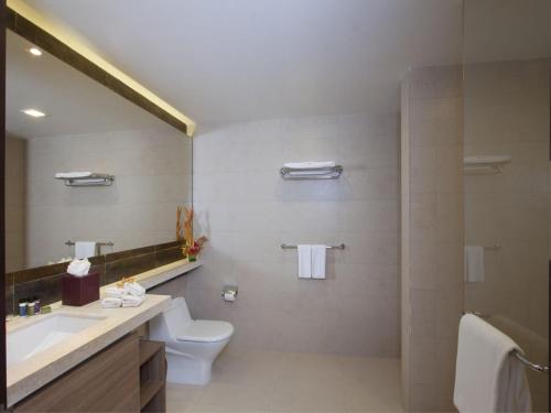 a bathroom with a toilet and a sink and a mirror at Oakwood Residence Whitefield Bangalore in Bangalore