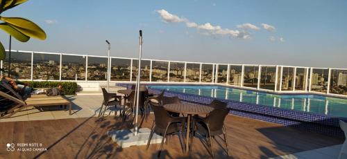 a patio with tables and chairs next to a swimming pool at Terraço Harmony Flats GRU in Guarulhos