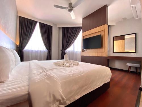 a bedroom with a white bed and a flat screen tv at Grace Hotel Semporna in Semporna