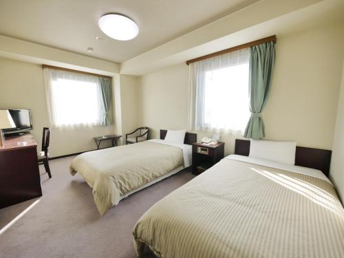 Hotel Route-Inn Shimada Ekimae في Shimada: غرفة فندقية بسريرين ونوافذ