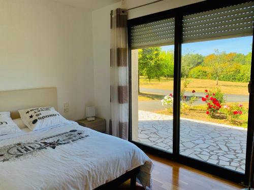 een slaapkamer met een bed en een grote glazen schuifdeur bij Villa du Bois Verts in Les Herbiers