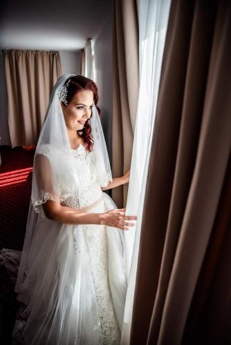 a woman in a wedding dress looking out of a window at Hotel Dennis in Mediaş
