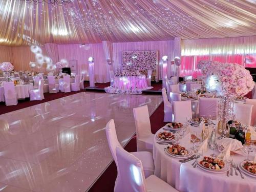 un salón de banquetes con mesas blancas, sillas y flores en Hotel Dennis, en Mediaş