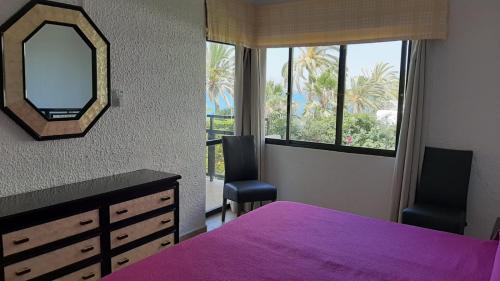 1 dormitorio con cama morada y espejo en Skol 134C by Completely Marbella, en Marbella