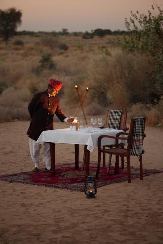 a man standing in front of a table with a candle at SUJÁN The Serai Jaisalmer in Jaisalmer