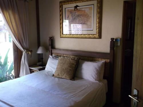 a bedroom with a white bed with a picture on the wall at Khandizwe Kruger Villa in Malelane
