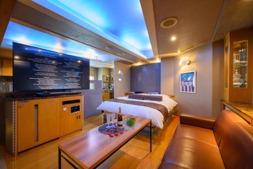 Water Hotel Mw (Love Hotel) في سايتاما: غرفة نوم بسرير وتلفزيون وأريكة