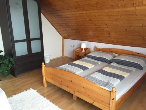 a bedroom with a wooden bed and a wooden ceiling at Cyrano Vendégház in Vonyarcvashegy