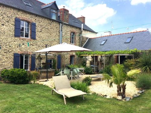 eine Terrasse mit einem Sonnenschirm und einem Stuhl im Hof in der Unterkunft La Maison in Les Forges