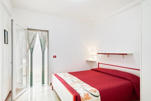Un dormitorio blanco con una cama roja y una ventana en Kartibubbo Village Experience, en Granitola