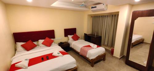 a hotel room with two beds and a mirror at Hotel Green Plaza in Trichūr