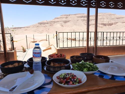 een tafel met borden en een fles water bij Malkata House in Luxor
