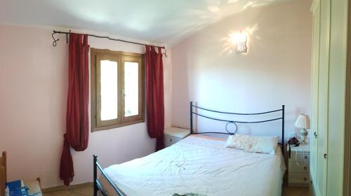 1 dormitorio con 1 cama y una ventana con cortinas rojas en Sardinia Sea Vacation Villa, en Costa Paradiso