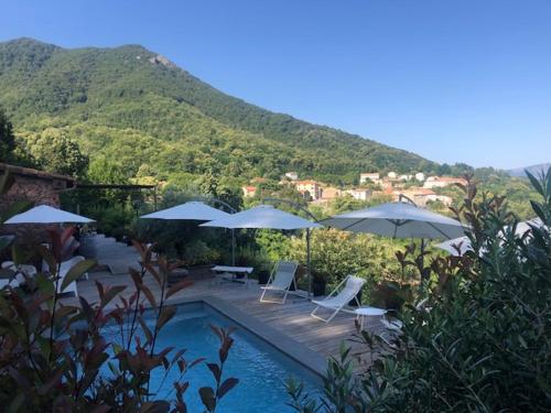 a swimming pool with umbrellas and chairs and tables at Casa Santa Lucia in Bocognano