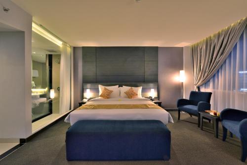 una habitación de hotel con una cama grande y una silla en Tjokro Hotel Pekanbaru, en Pekanbaru