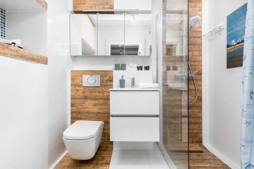 a white bathroom with a toilet and a shower at Apartament Mariner by Renters in Kołobrzeg