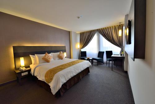 a hotel room with a large bed and a desk at Tjokro Hotel Pekanbaru in Pekanbaru