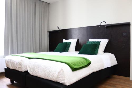 uma cama grande com cobertores e almofadas verdes e brancos em Revelatio, dé logies em Ypres