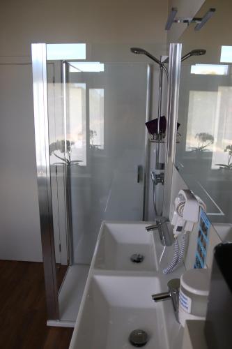 La salle de bains blanche est pourvue d'une douche et d'un lavabo. dans l'établissement Revelatio, dé logies, à Ypres
