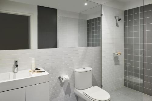 a bathroom with a toilet and a sink and a mirror at Punthill Oakleigh in Oakleigh