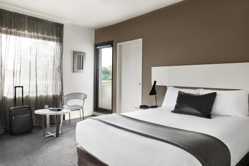 a hotel room with a large bed and a large window at Punthill Oakleigh in Oakleigh