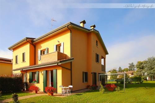 a yellow house with two chairs and a yard at B&B Il Guado in Voghenza