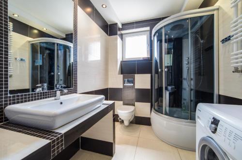 a bathroom with a sink and a washing machine at Aurora Apartament Gardenia in Międzywodzie