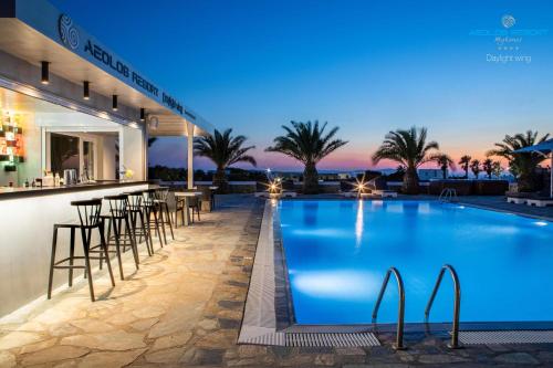 a hotel with a bar and a swimming pool at night at Aeolos Resort in Mikonos