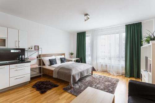1 dormitorio con cama, TV y cortinas verdes en Golden Apartments Rezidence Nová Karolina en Ostrava