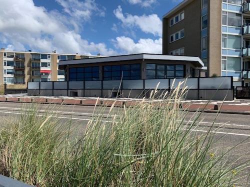 a building on the side of a street with tall grass at beach apartments in Zandvoort
