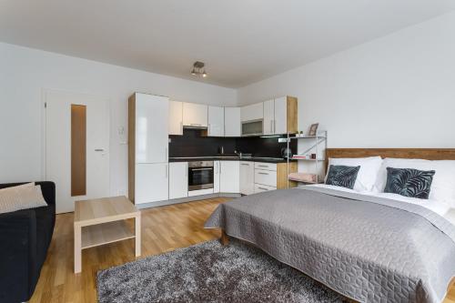 a bedroom with a large bed and a kitchen at Golden Apartments Rezidence Nová Karolina in Ostrava