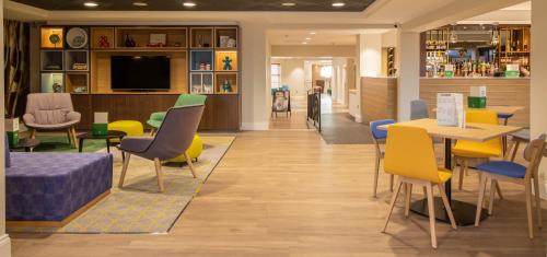 a waiting room with colorful chairs and tables at Holiday Inn - Leicester - Wigston by IHG in Leicester
