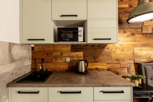 a kitchen with a sink and a microwave at BAB-LAK Apartman in Kisvárda