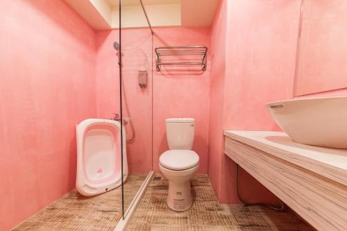 羅東鎮的住宿－羅東夜市坦智能旅店 ，粉红色的浴室设有卫生间和水槽