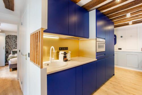 une cuisine avec des armoires bleues et un évier dans l'établissement Charming apartment - 1BR-4P - Le Marais, à Paris