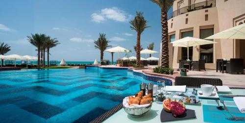 a pool at a resort with a table with bread on it at Bahi Ajman Palace Hotel in Ajman 
