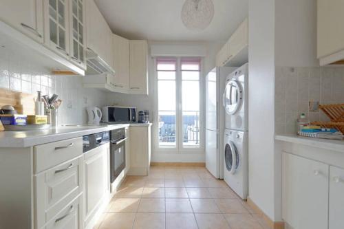 uma cozinha com electrodomésticos brancos e uma grande janela em Appartement Disneyland au centre du Val d'Europe em Chessy