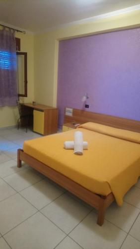 マルゲリータ・ディ・サヴォイアにある"Casa di Rosa"のベッドルーム1室(紫の壁の黄色いベッド1台付)