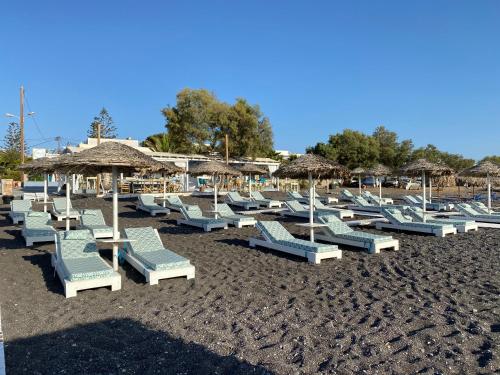 a group of lounge chairs and umbrellas on a beach at Kalya Suites in Kamari