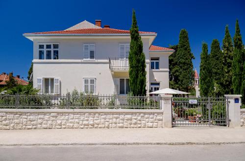 ein großes weißes Haus mit einem Zaun und Bäumen in der Unterkunft Palace Schön Milesi - esense of prestige - BURALUX properties in Split