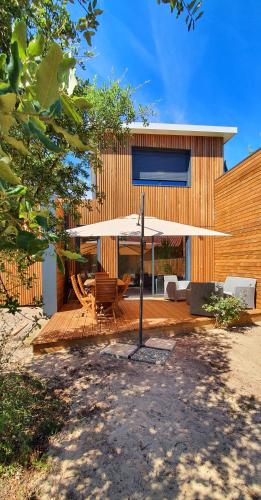 a wooden deck with a table and an umbrella at Villa 3 chambres Contis-plage à 900m de l océan in Lit-et-Mixe