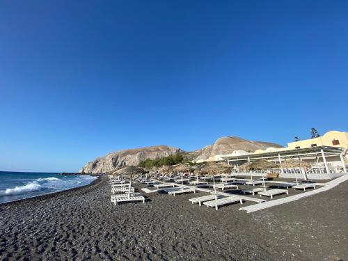 a group of lounge chairs on a black beach at Kalya Suites in Kamari