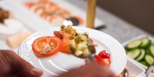 a person holding a plate with tomatoes on it at Historische Spitzgrundmühle in Coswig