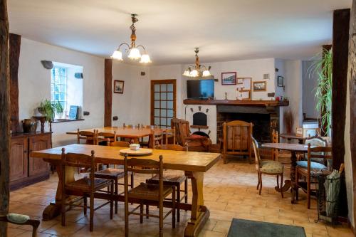 Ferme Laurens في Bartrés: غرفة طعام مع طاولات وكراسي ومدفأة