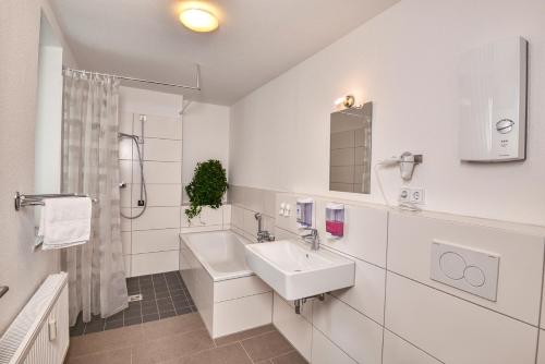 uma casa de banho branca com um lavatório e um chuveiro em Hostel am Niederfeldsee em Essen