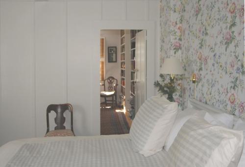 a bedroom with a bed and a chair and a mirror at 29 India House in Nantucket