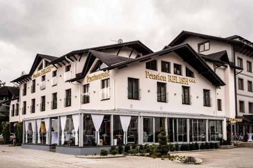 a large white building with black roof at Pension Relish in Rajecké Teplice