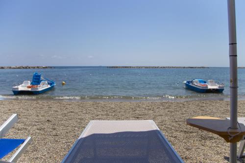 a beach with a mat and boats in the water at Hotel Mayola in San Bartolomeo al Mare